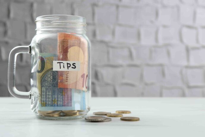 tips-jar-with-money-on-white-marble-table-space